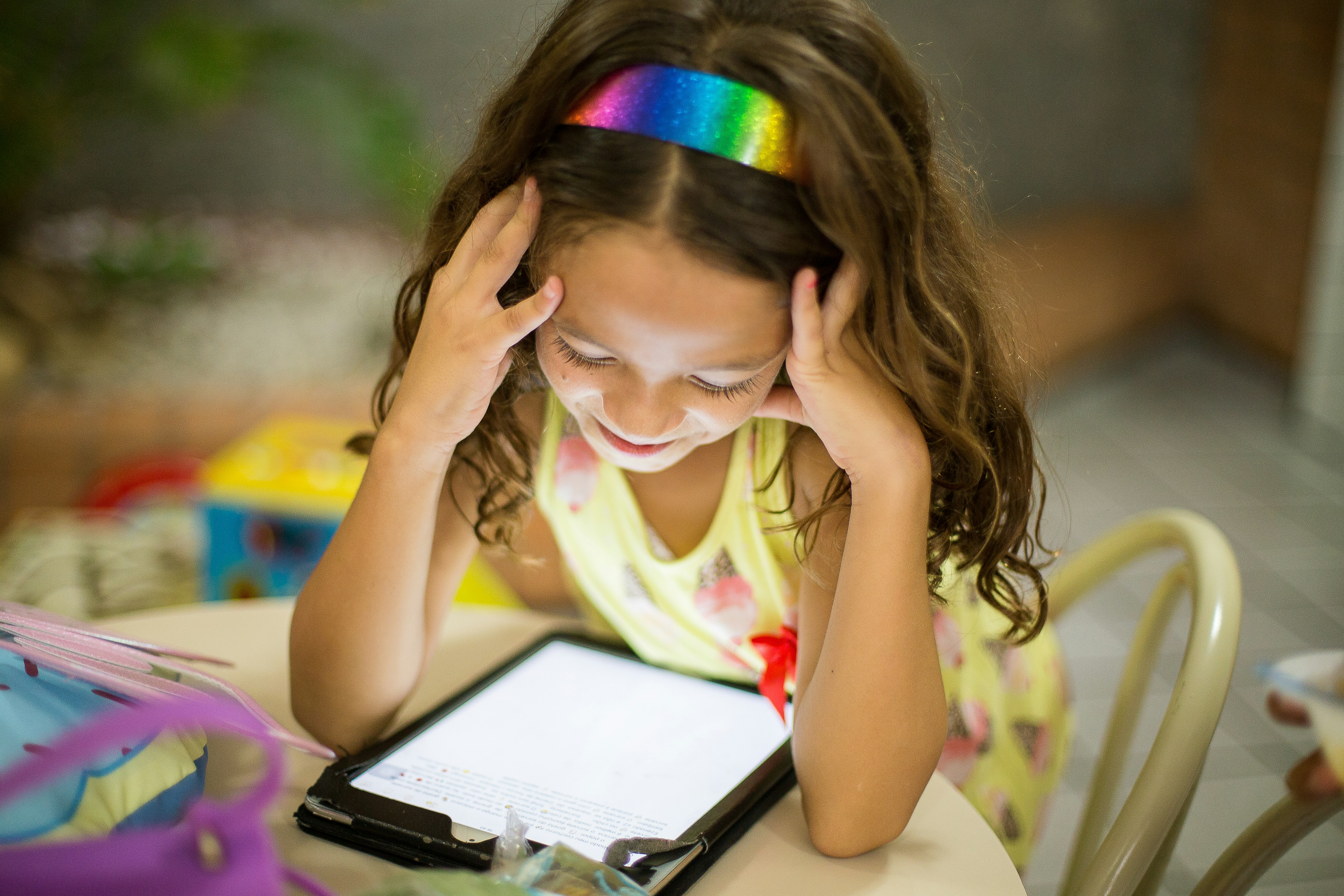 child sitting and looking at an electronic tablet
