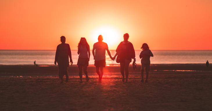 family walking on a beach at sunset 