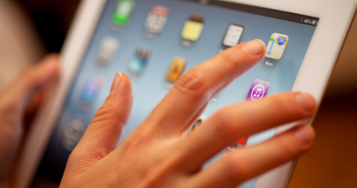 A finger taps the screen of an ipad