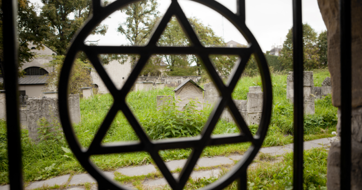 A Star of David on a gate to a cemetery with tombstones in background