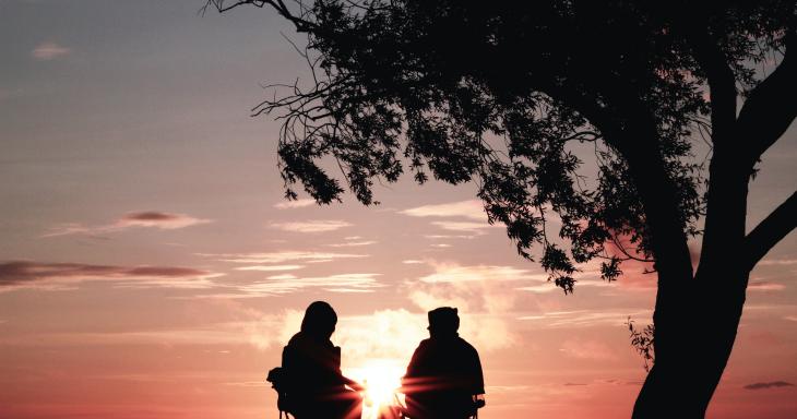 two people sitting at sunset talking