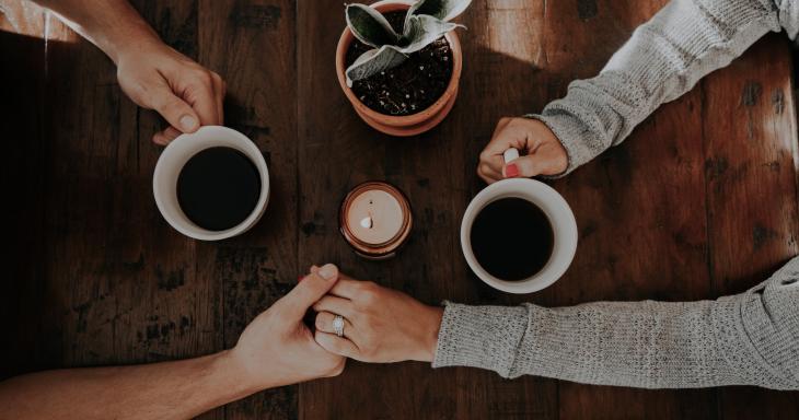 Two people holding hands over coffee. 