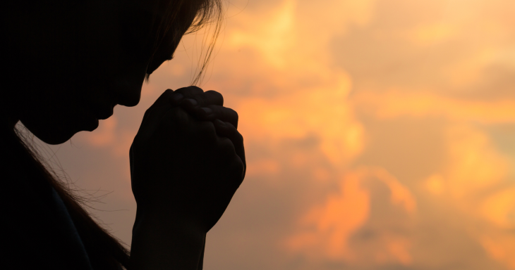 a girl's silhouette as she prays against a sky
