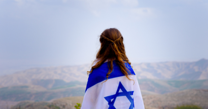 Girl with Israeli flag wrapped around her faces mountains
