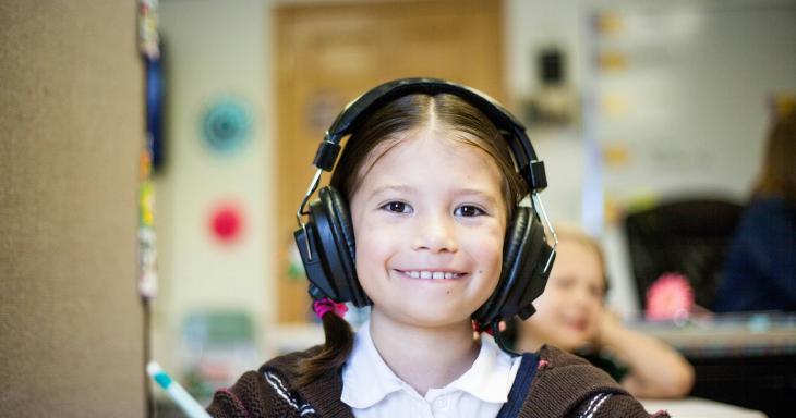 young girl holding pencil with headphones on