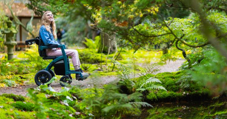 Person in wheel chair on wooded path 