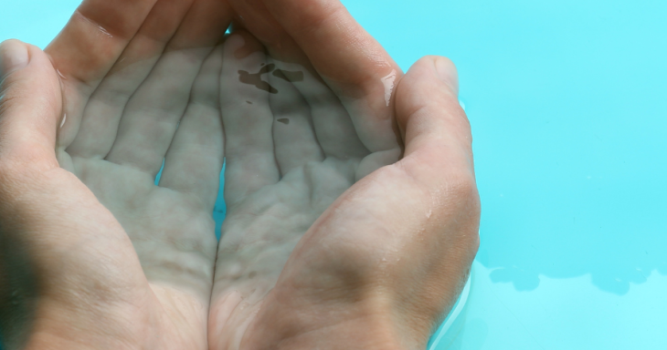 Two hands cupping clear, blue water.