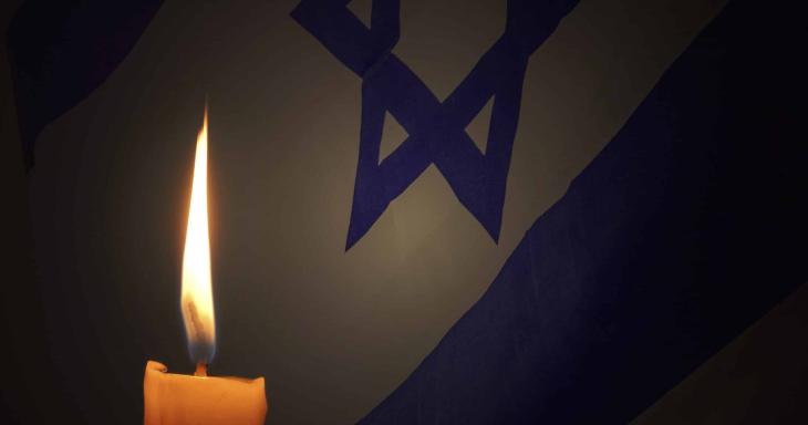 Candle burning in front of an Israeli flag