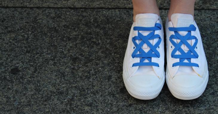 A picture of someone wearing white converse, with royal blue laces arranged in a Jewish star.