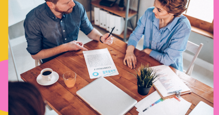 two people signing documents at a table