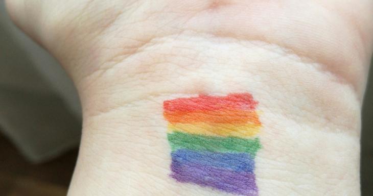 White open palm with a rainbow painted on the wrist