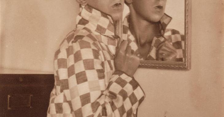 Claude Cahun standing in front of a mirror with reflection.