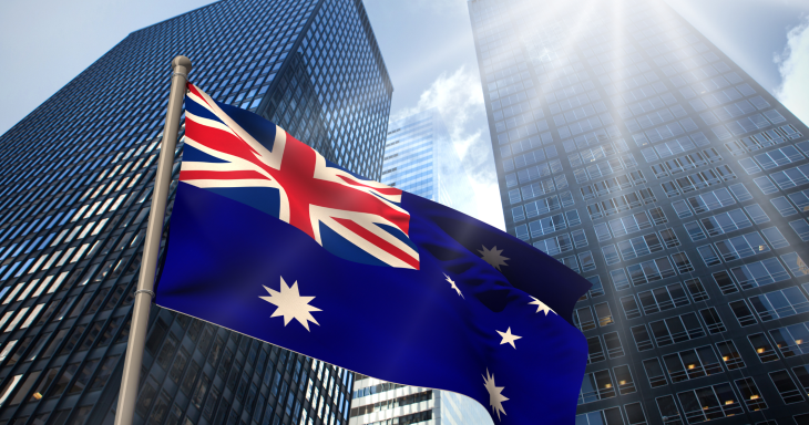 Australian flag hangs on a pole with buildings in background