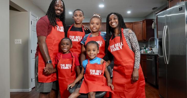 A photo of a family in aprons posing and smiling together.