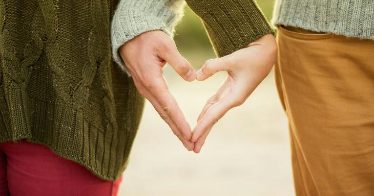 Two people holding hands in the shape of a heart