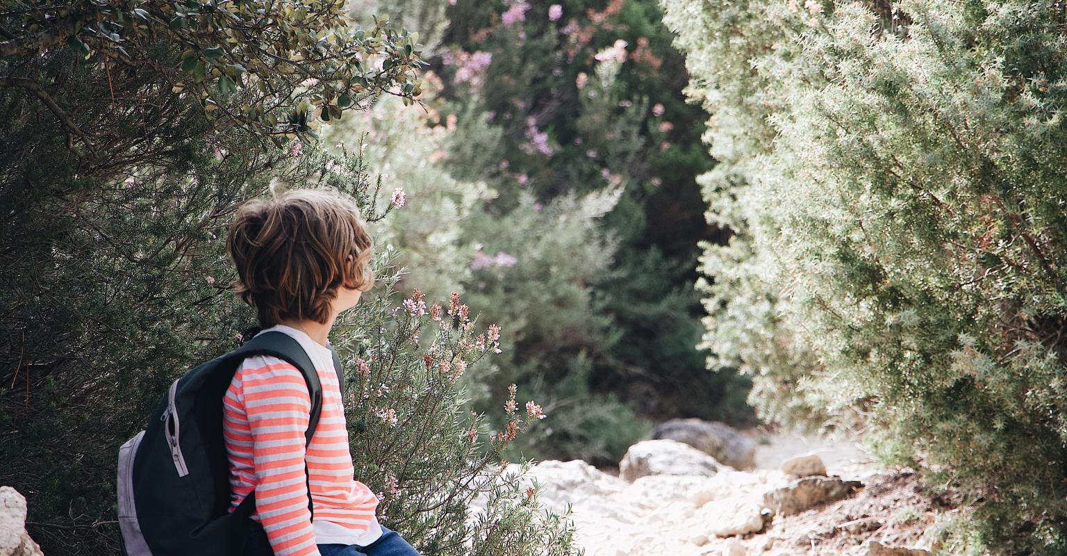 Child out in a natural setting with a school backpack on.