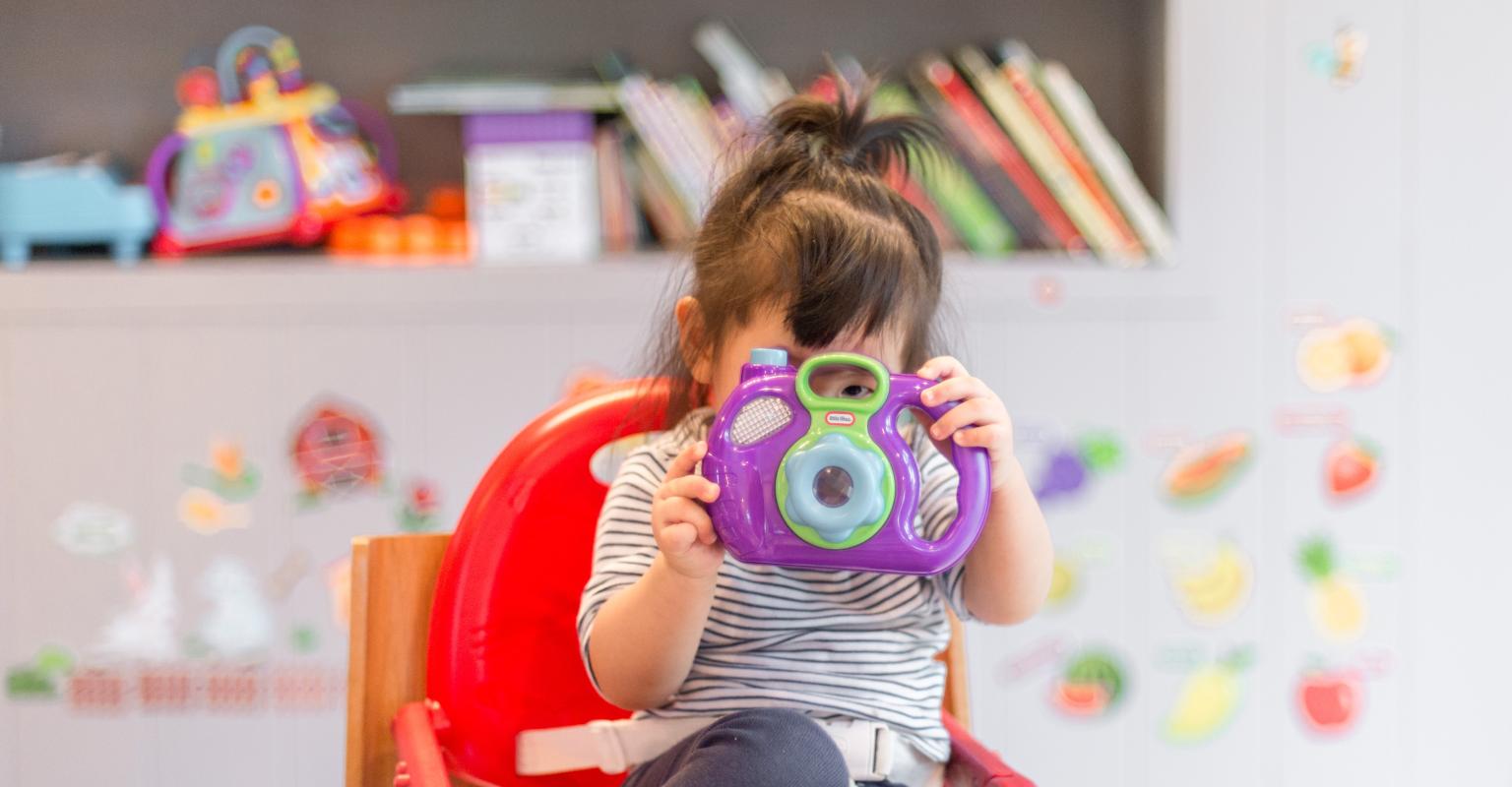 Preschool child looking through toy camera