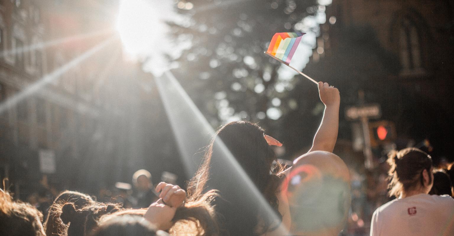 People walking together and a pride flag being held up