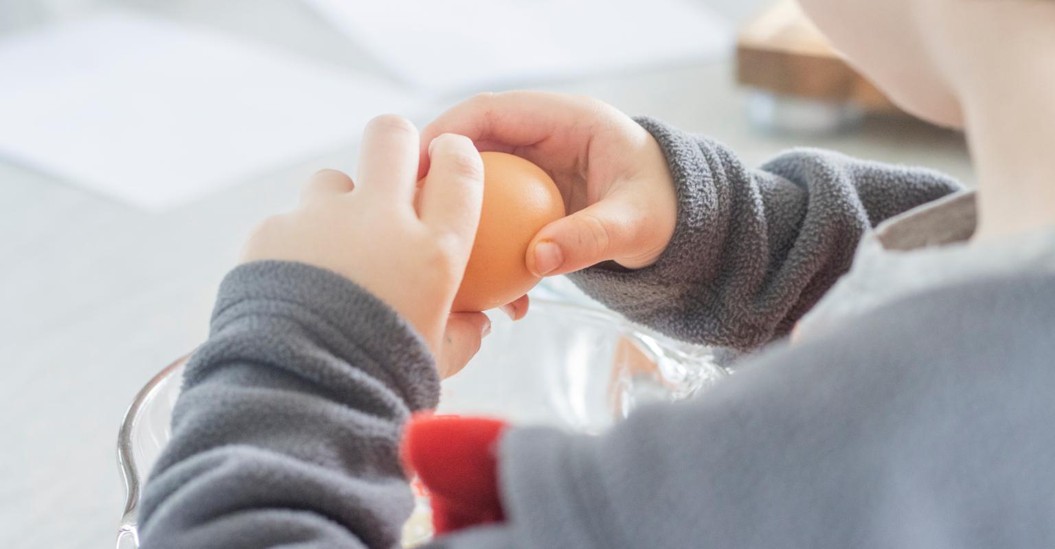 Child cracking an egg into a bowl