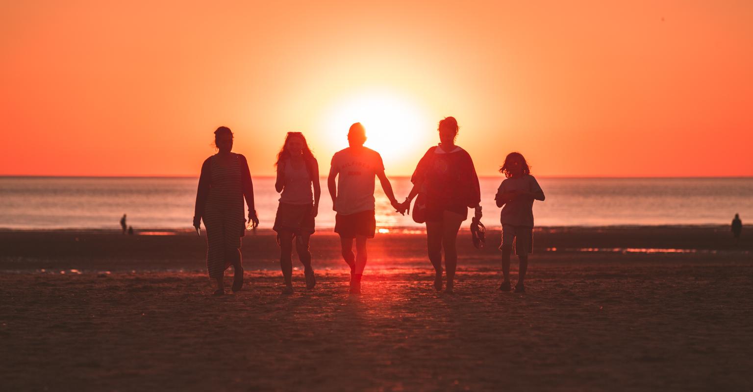 family walking on a beach at sunset