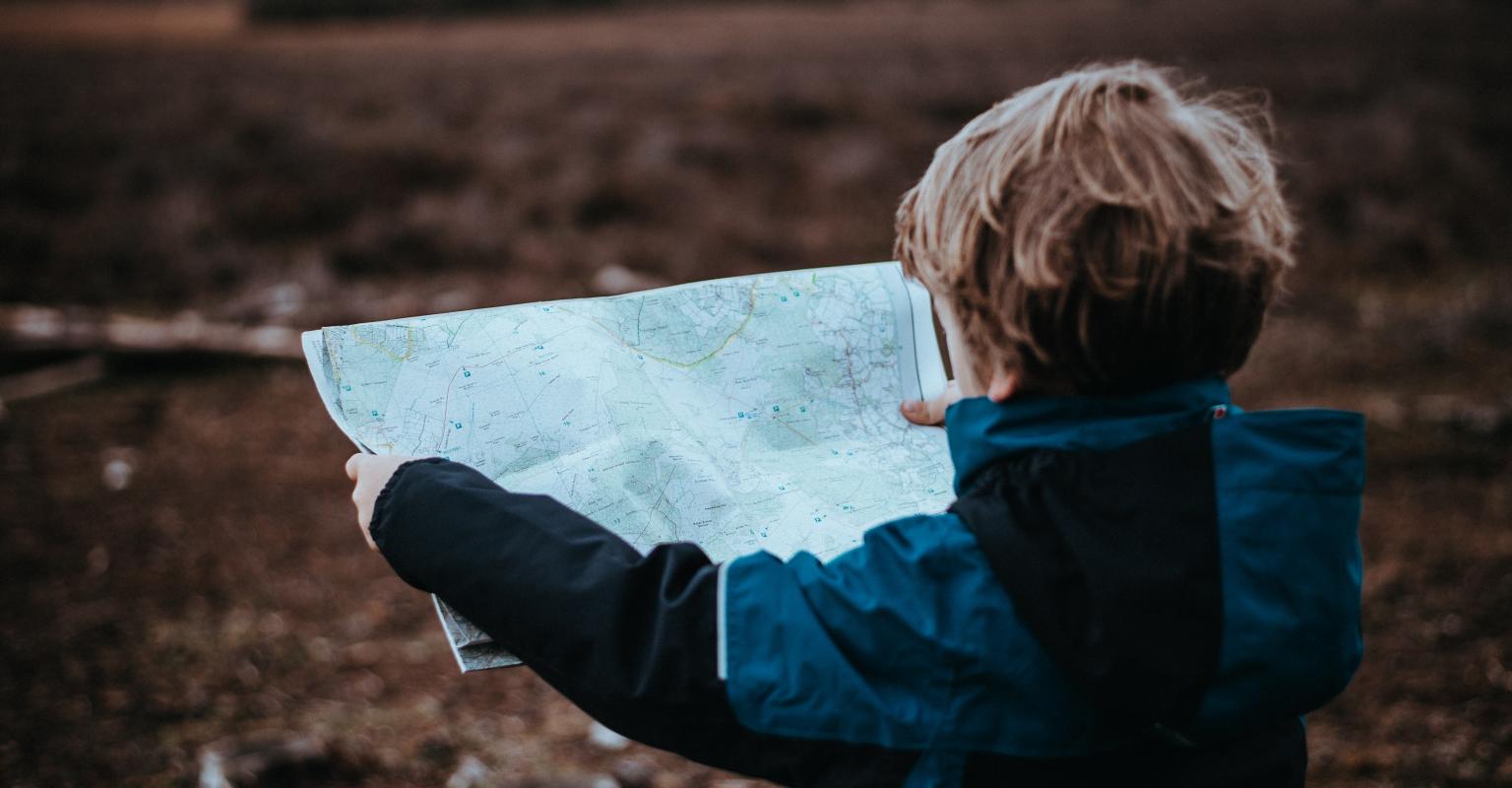 Child reading a map outdoors.