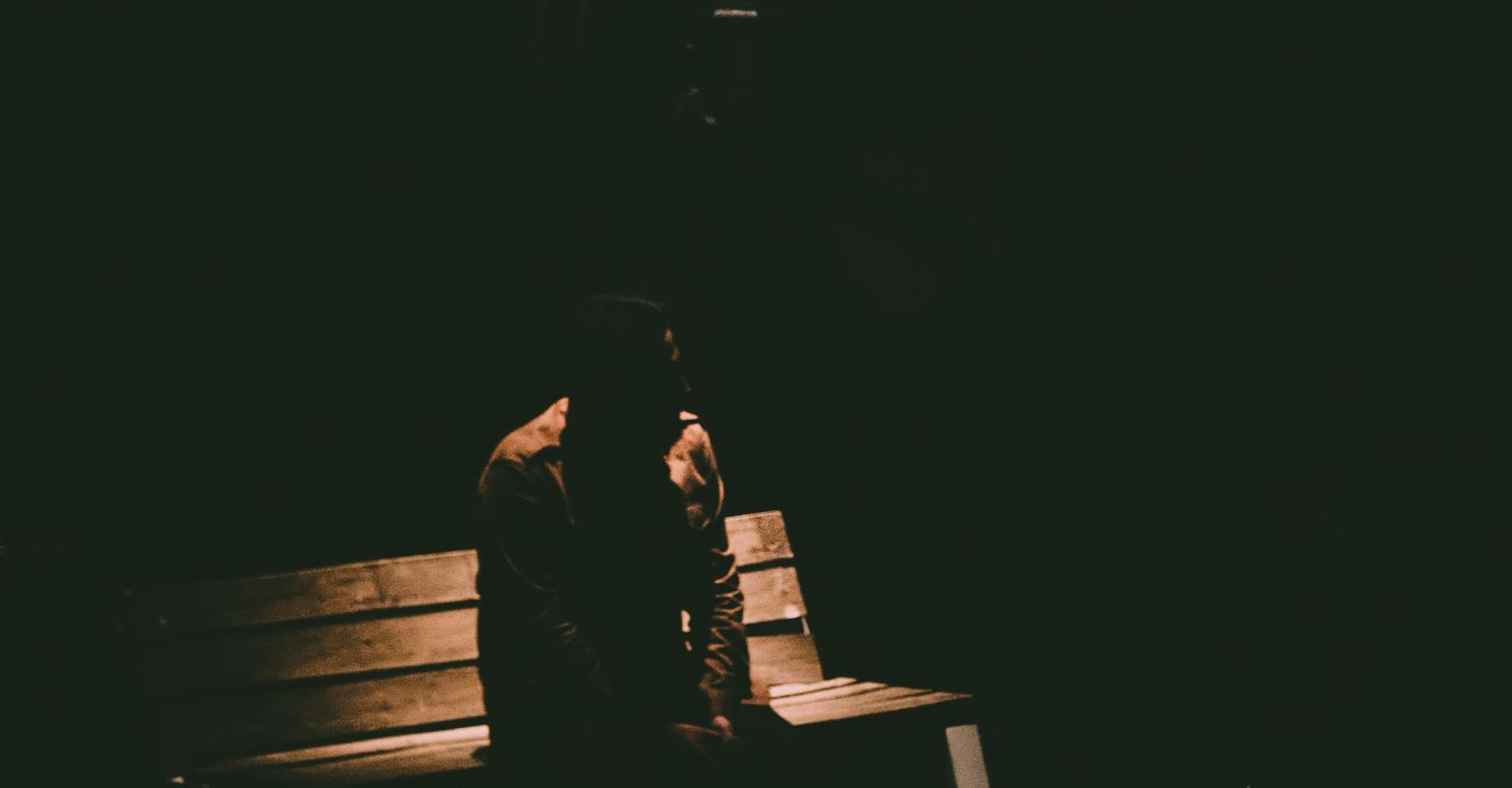 Person on bench in darkness