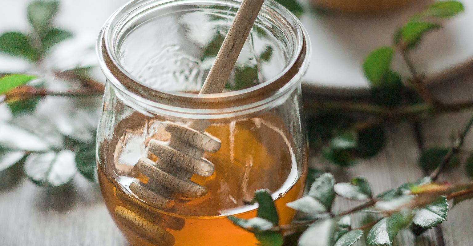 Pot of honey with apple pastry in the background
