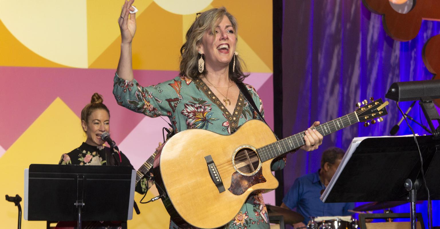 Naomi Less on stage with a guitar