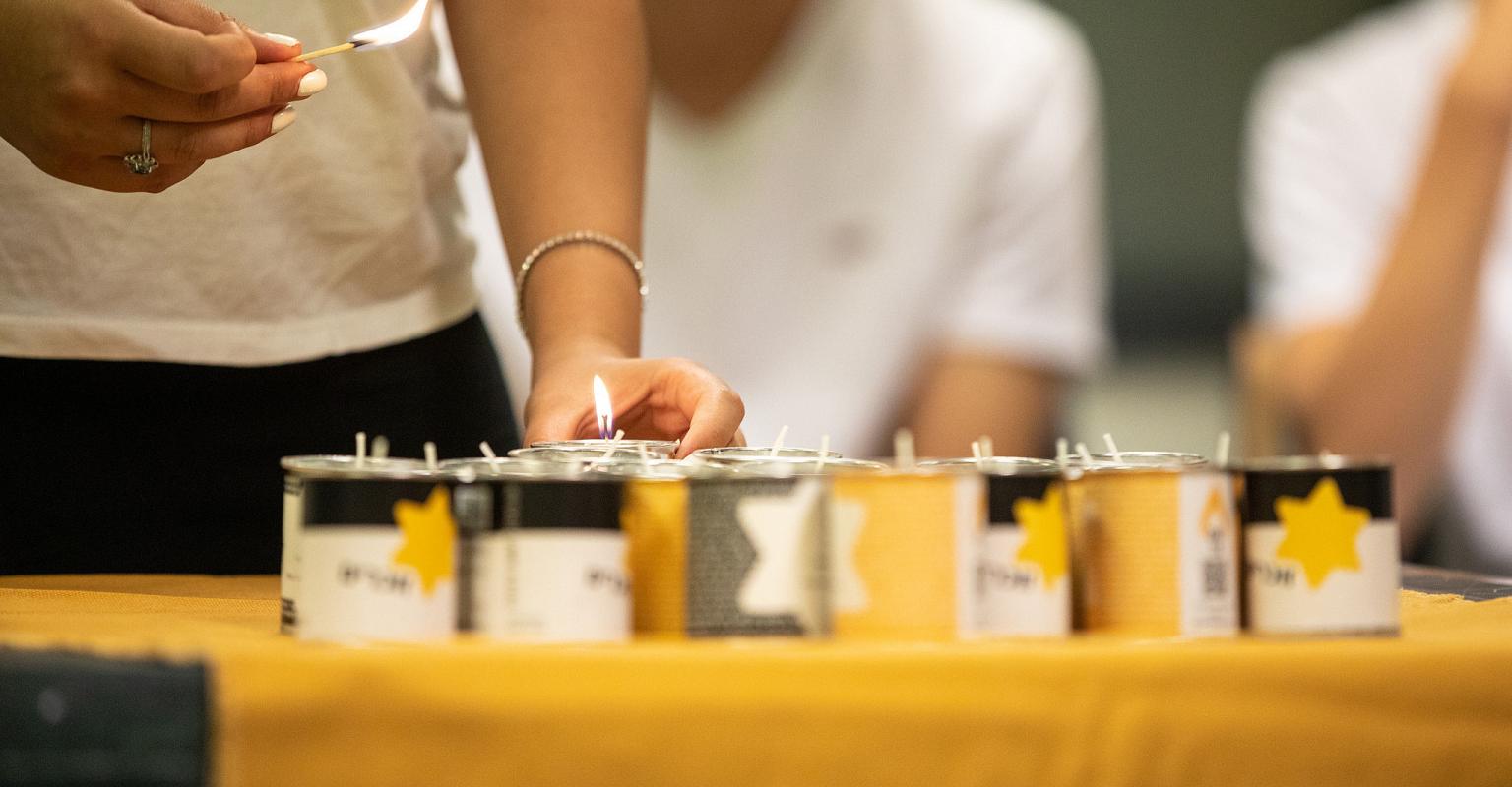 hands lighting yartzeit candles.