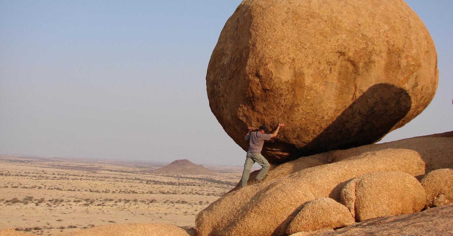 Person pushing large rock