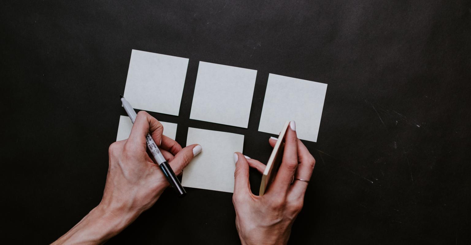 An educator writing on post its on a wooden table.