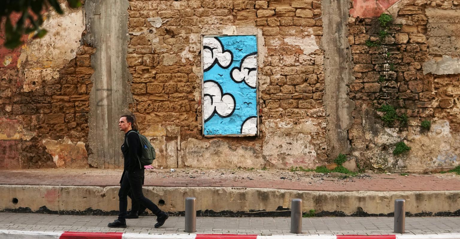 A window-shaped artwork, set in a wall in a street in Jerusalem. 