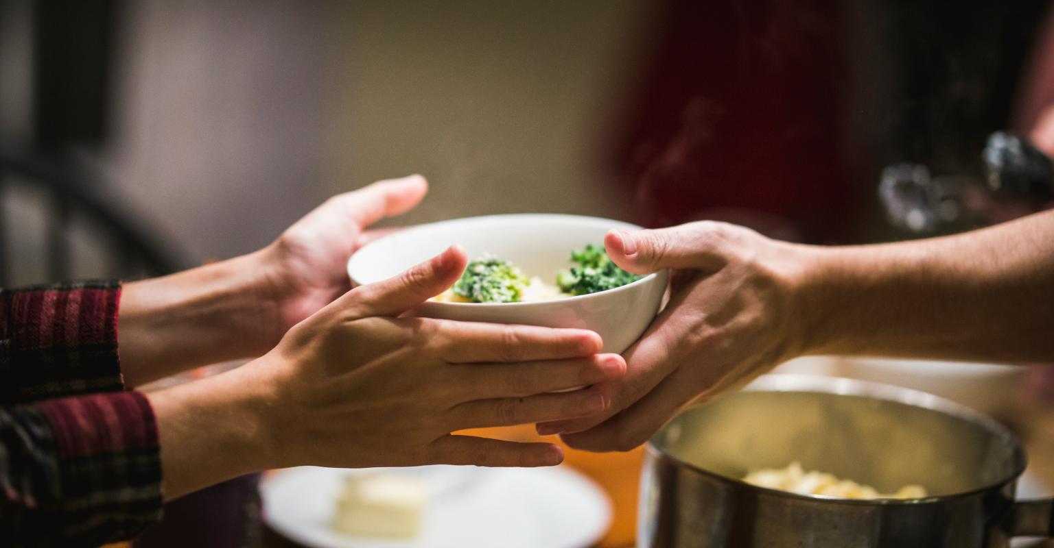 Bowl of food passing from one hand to another