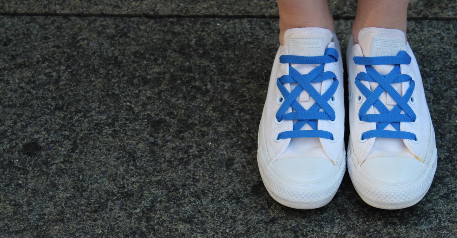 A picture of someone wearing white converse, with royal blue laces arranged in a Jewish star.