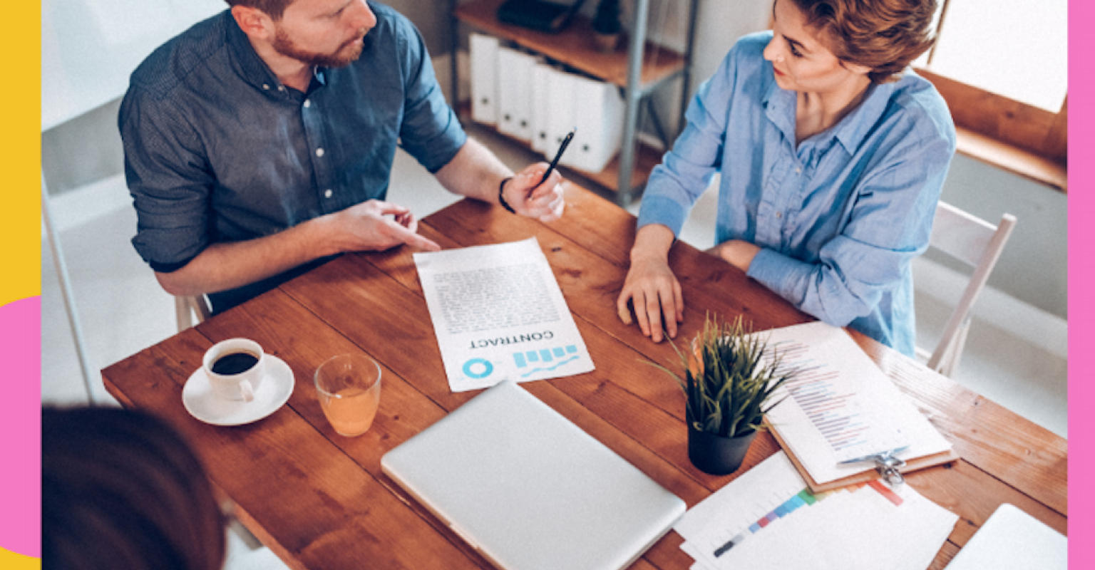 two people signing documents at a table