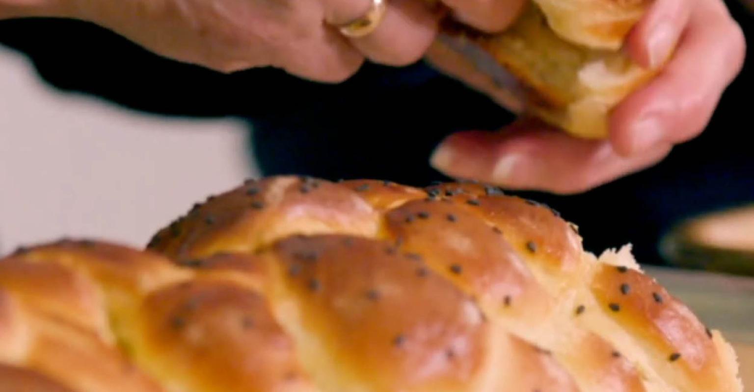 Picture of a woman's hands breaking apart challah.