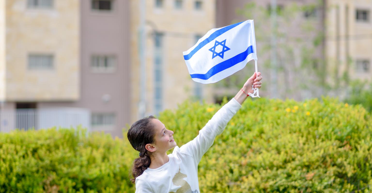 A young student holding an Israeli flag.
