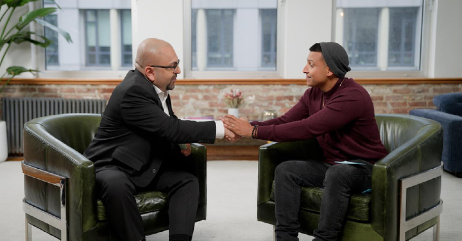 Two men in seated positions shaking hands