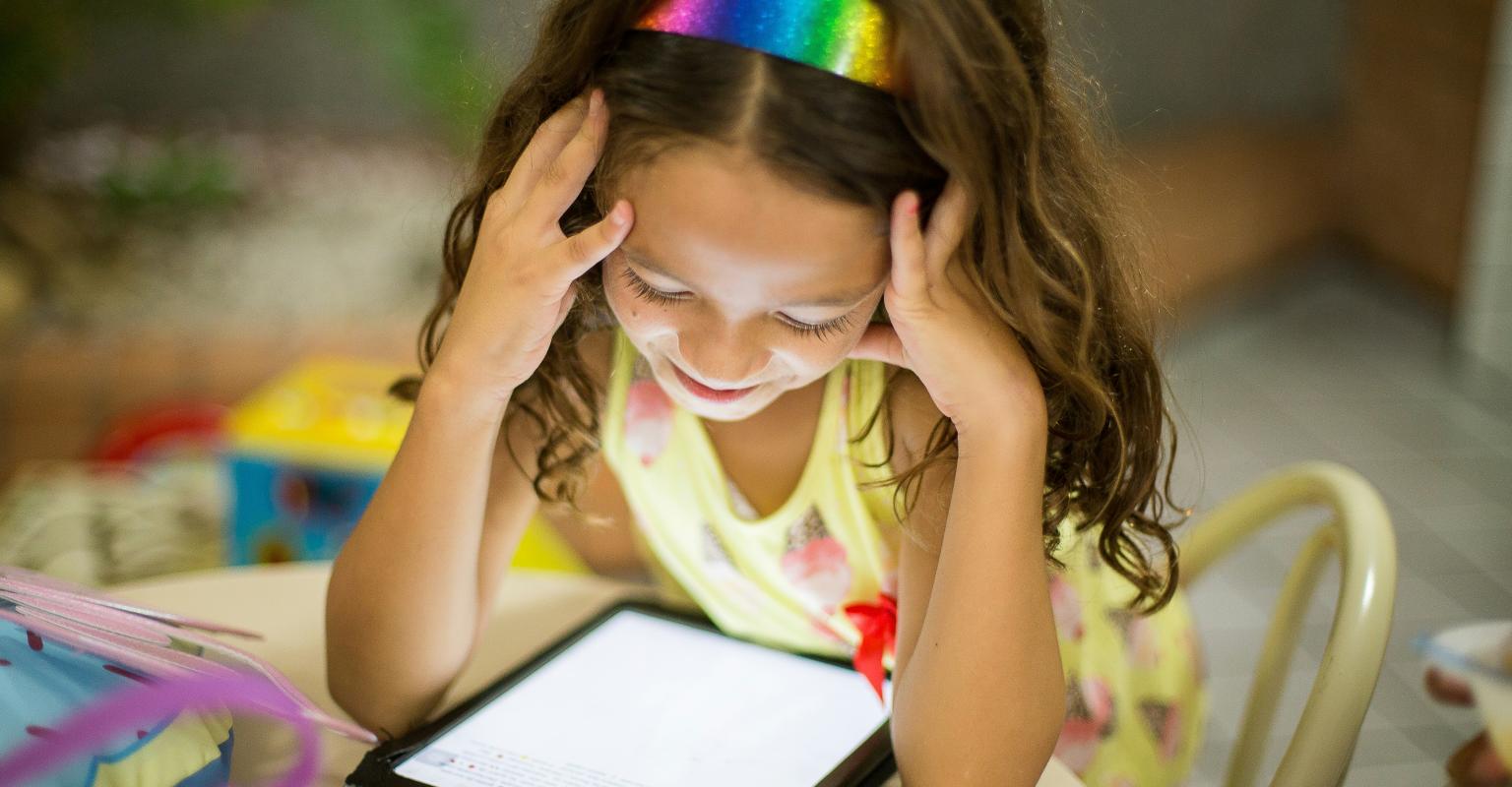 child sitting and looking at an electronic tablet