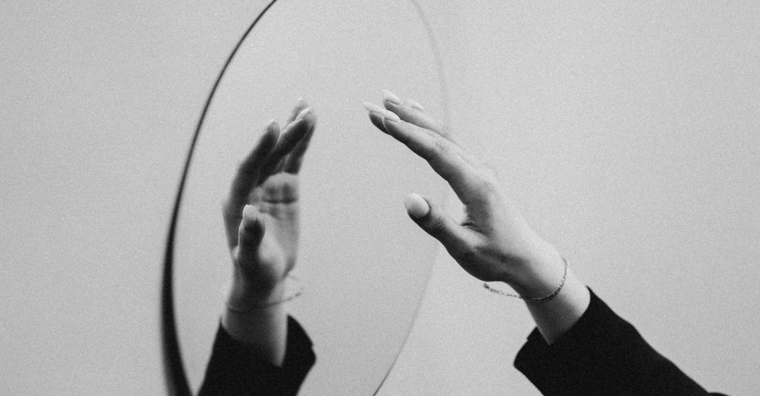 Hand reaching out at mirror