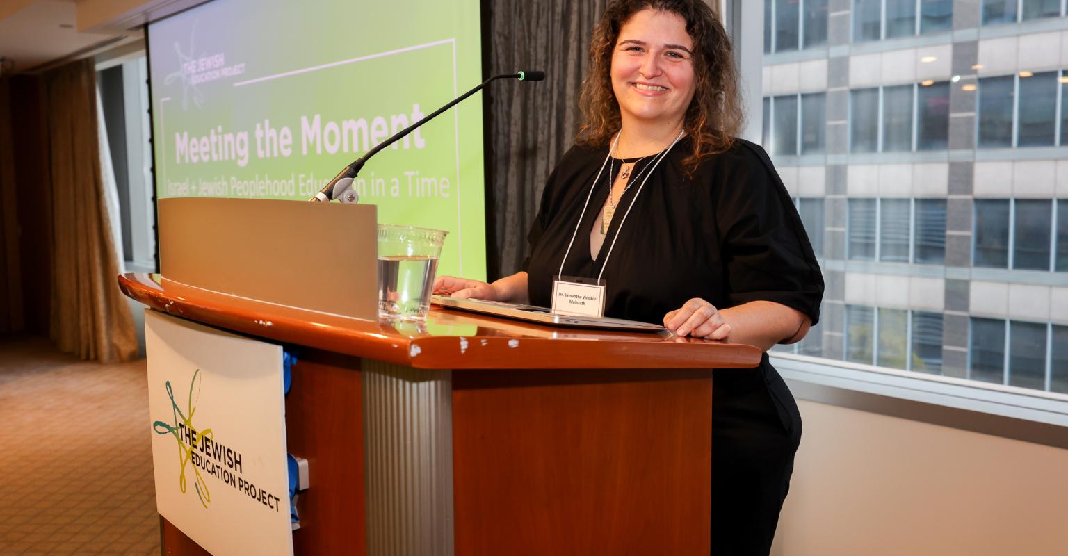 Samantha stands at a podium and smiles