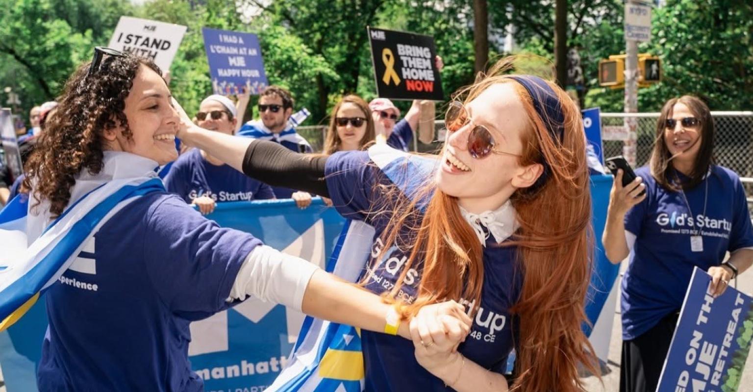 two girls dancing with israeli flags tied around them