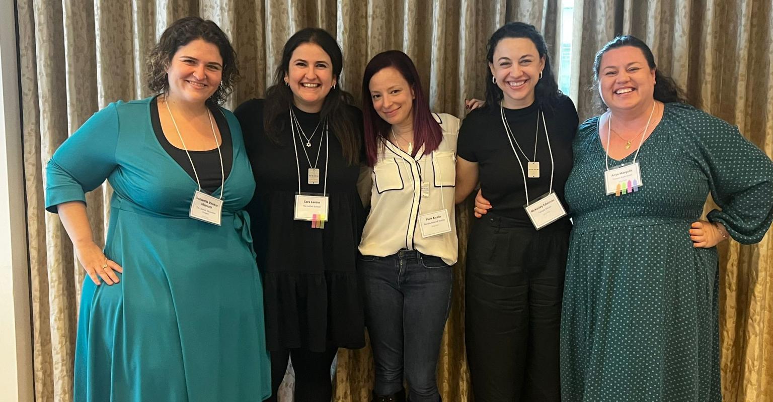 a group of women pose with arms around each other, each with nametags around their necks
