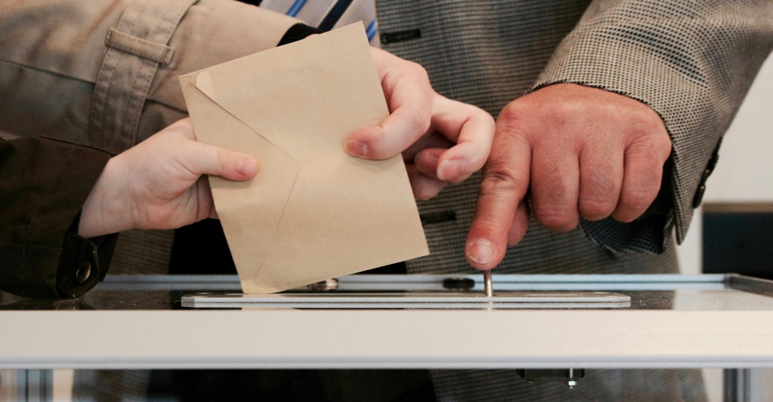 voting envelope being placed in box