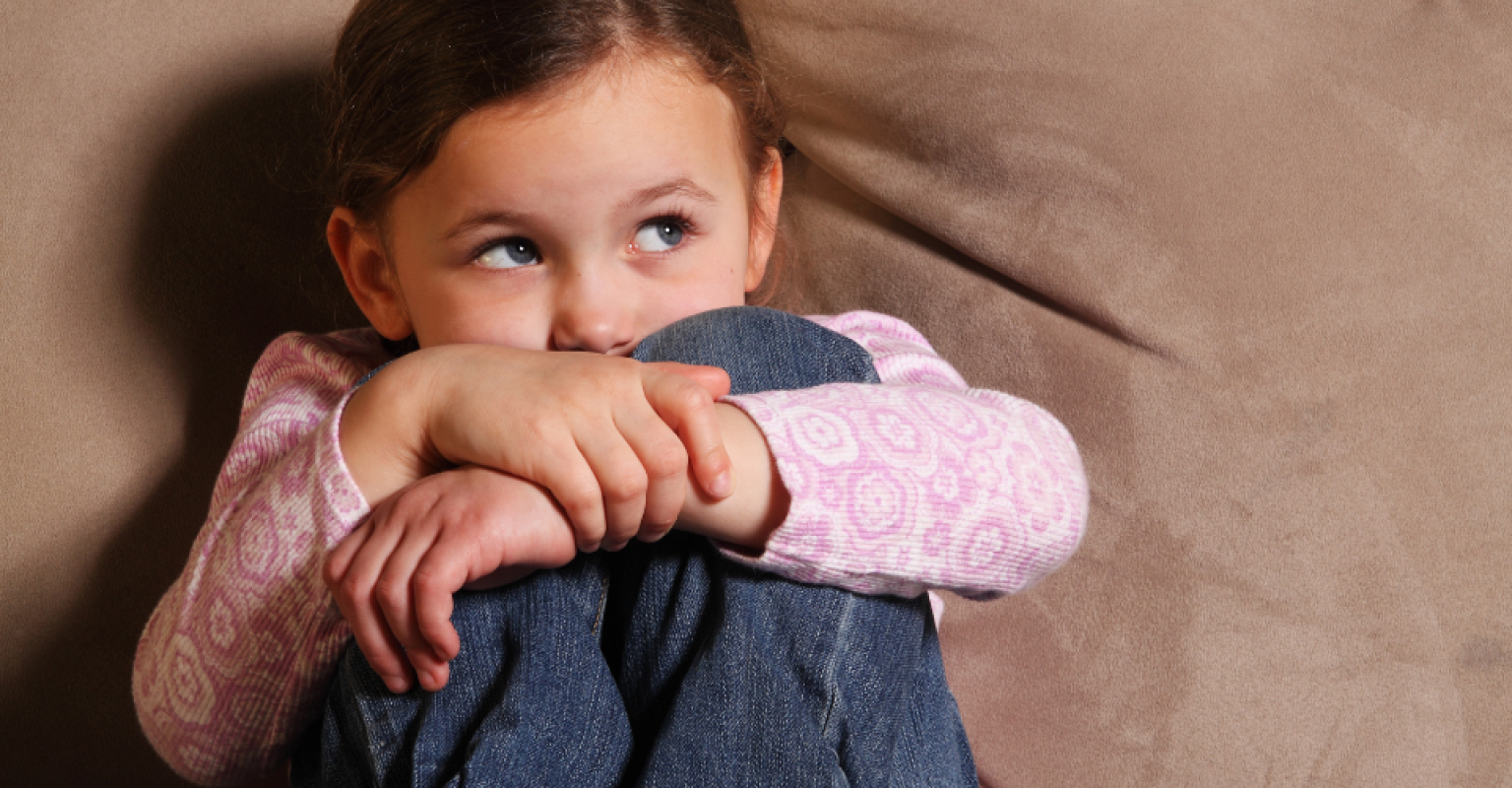 a little girl crouches looking scared