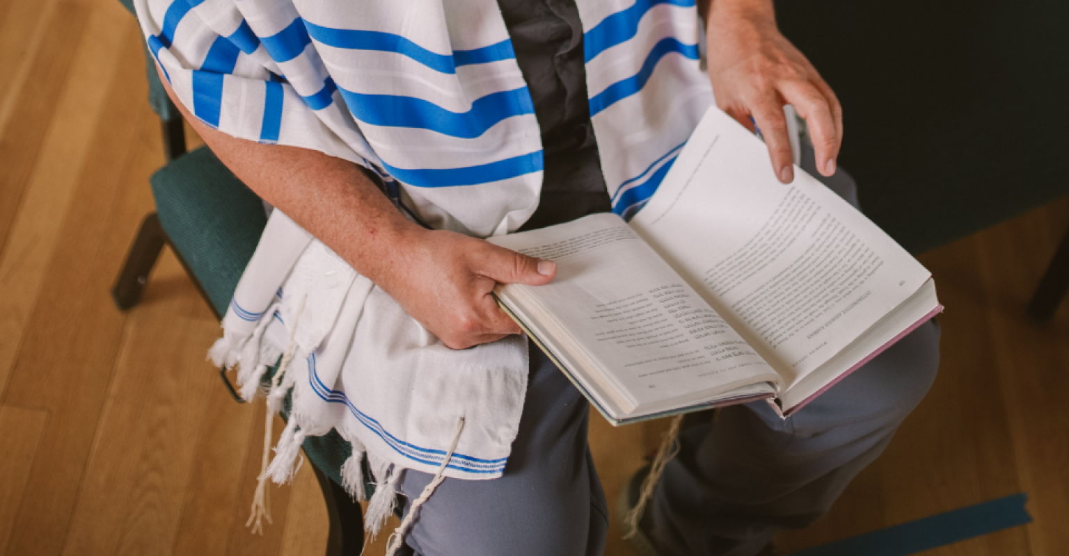 a closeup of a rabbi with a tallis holding a prayer book