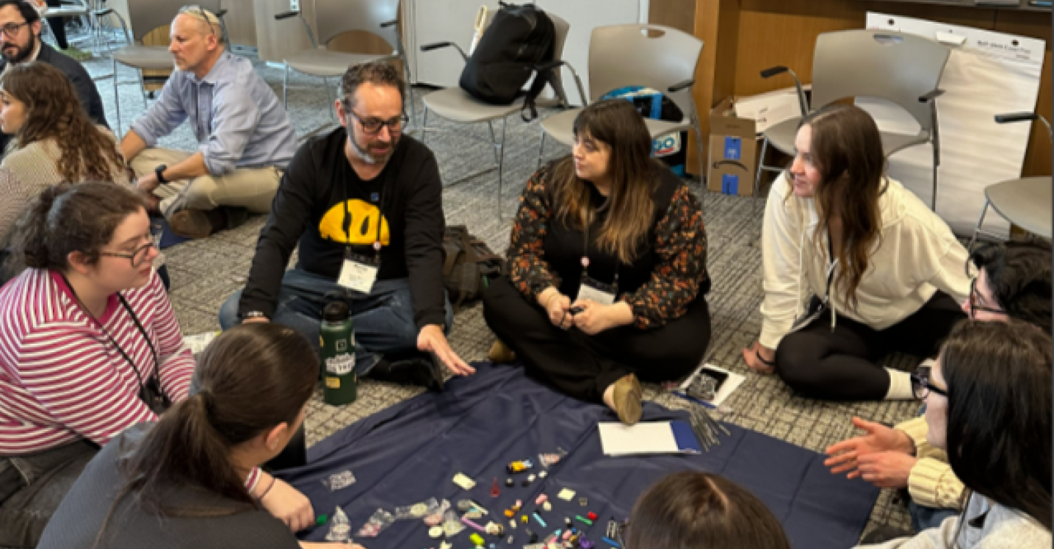 Group of adults sitting on the floor engage in discussion 