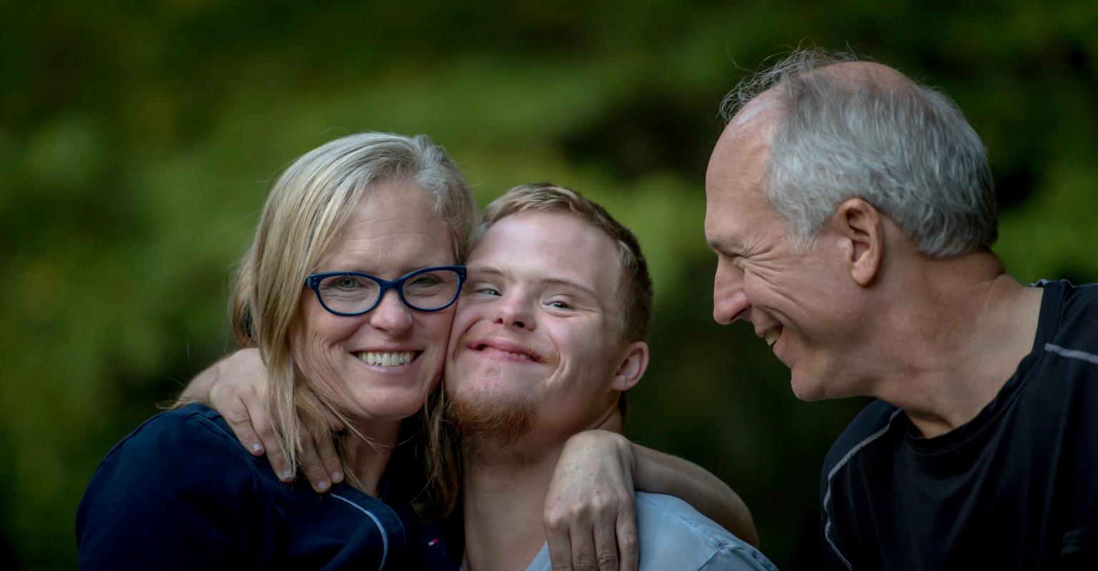 two parents hug their son with Down Syndrome