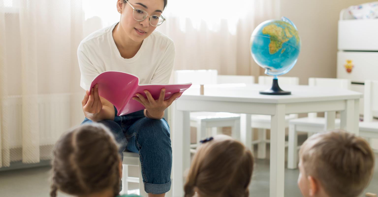 Woman reading to her students. Table with a globe on it in the background