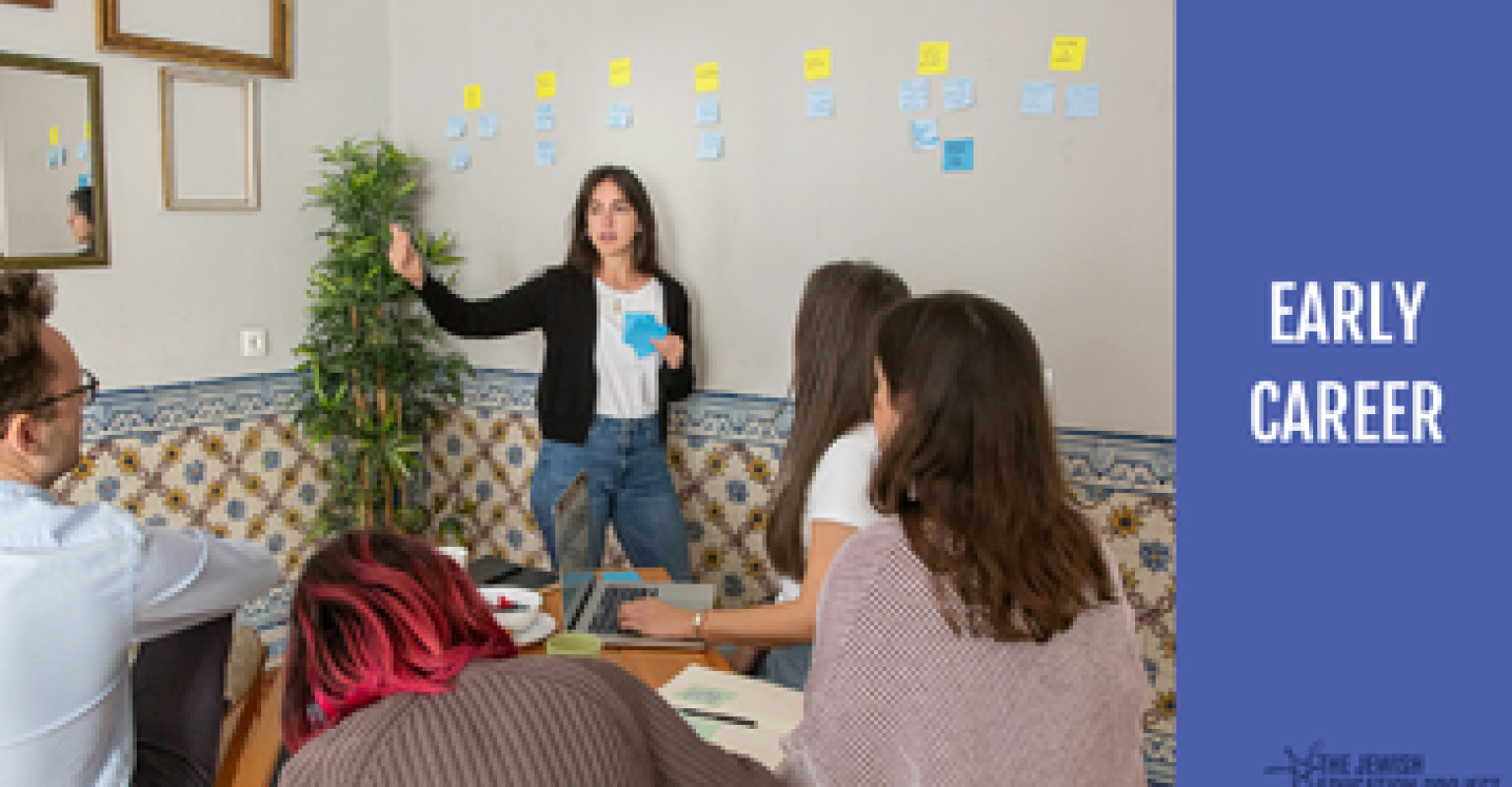 "Early Career" banner. Facilitator standing and speaking with sticky notes behind them. Participants sit at a table. 
